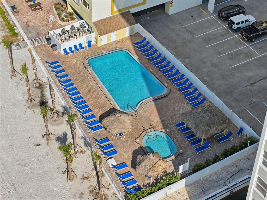 An aerial view shows a swimming pool and hot tub surrounded by lounge chairs — 17450 GULF BOULEVARD UNIT 104, REDINGTON SHORES, FL