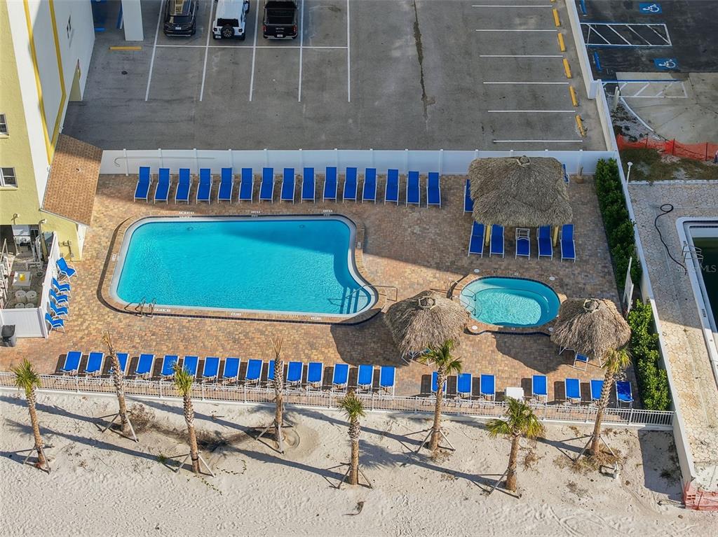An aerial view shows a swimming pool, hot tub, tiki huts, and lounge chairs — 17450 GULF BOULEVARD UNIT 104, REDINGTON SHORES, FL