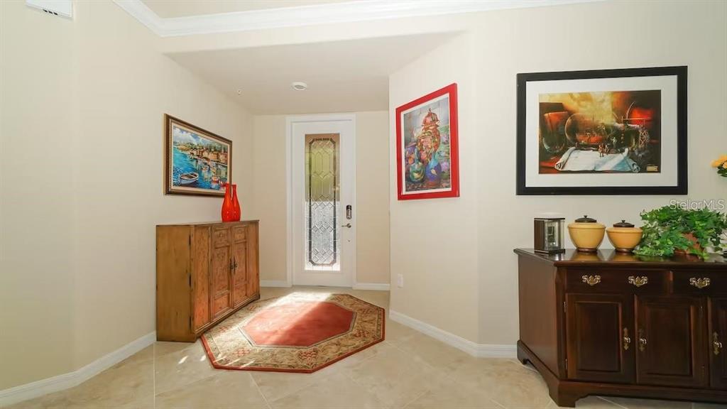 An entryway features tile flooring, a wooden cabinet, a rug, and a front door — 6614 GRAND ESTUARY TRAIL UNIT 101, BRADENTON, FL