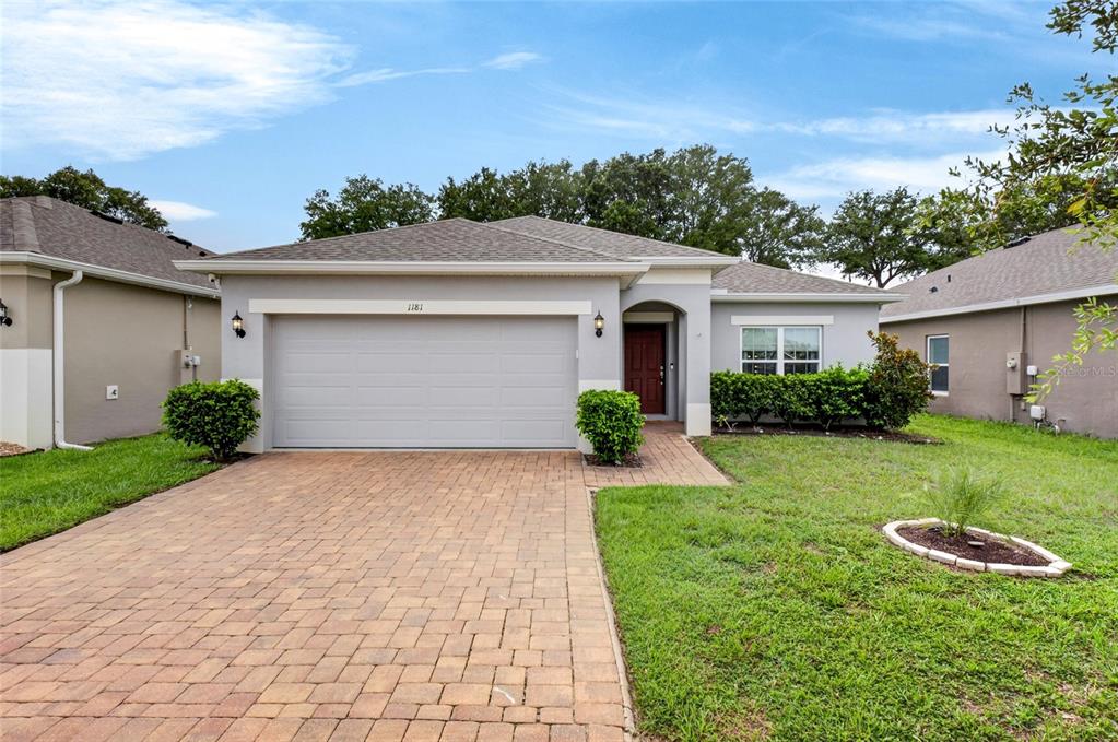 A single-story house with a gray exterior, a two-car garage, and a brick paver driveway — 1181 STRATTON AVENUE, GROVELAND, FL