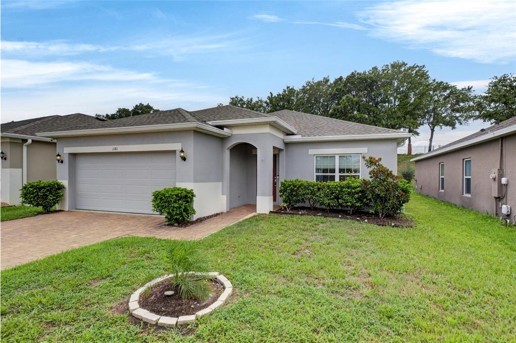 A single-story gray house with a two-car garage, paved driveway, and front landscaping — 1181 STRATTON AVENUE, GROVELAND, FL
