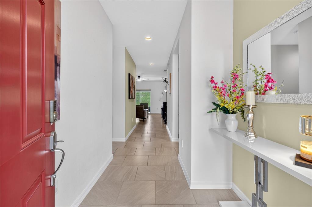 A red front door opens into a tiled entryway hallway leading toward a living area — 1181 STRATTON AVENUE, GROVELAND, FL