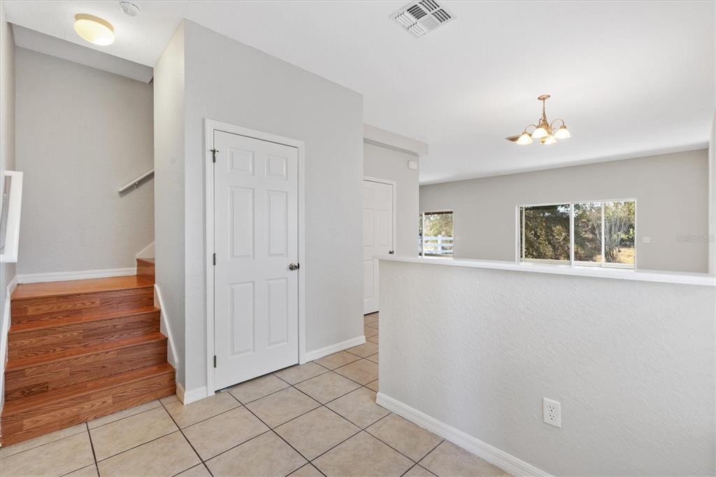 An interior view shows a tiled entryway with wooden stairs and a partial wall divider — 5186 NE 122ND BOULEVARD, OXFORD, FL