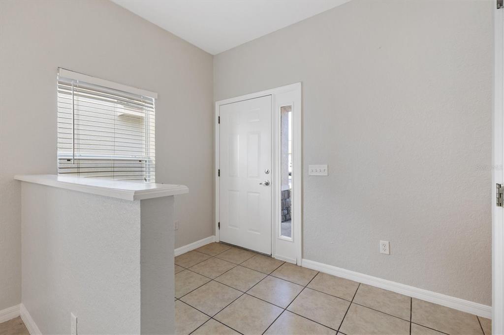 An entryway features light-colored walls, tiled flooring, a white front door, and a half wall — 5186 NE 122ND BOULEVARD, OXFORD, FL