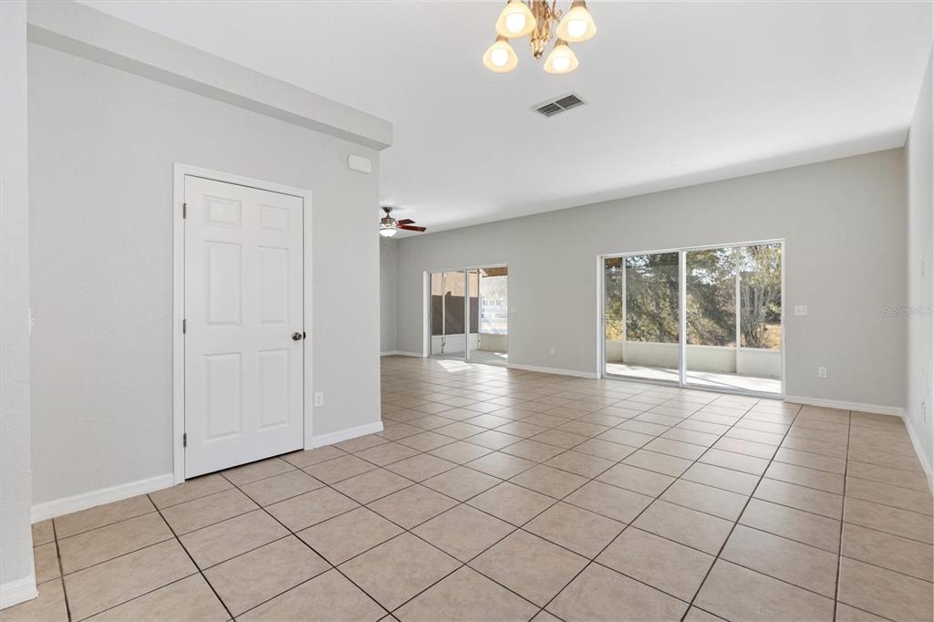 A spacious room with light-colored tile flooring, white walls, and two sliding glass doors — 5186 NE 122ND BOULEVARD, OXFORD, FL