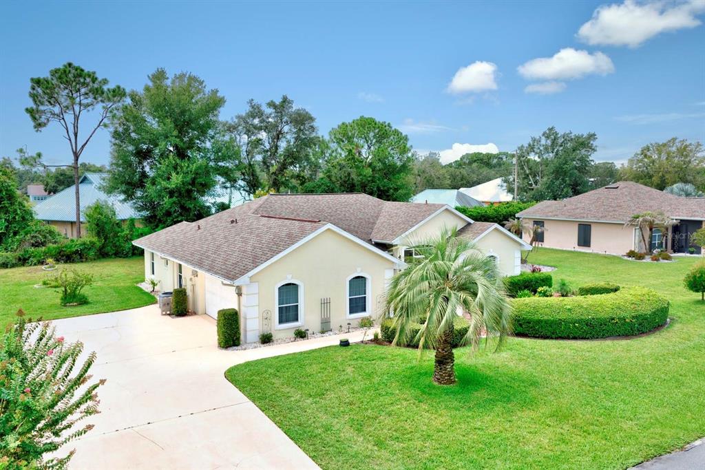 An exterior view of a single-story house with a tan facade, shingled roof, and lawn — 4253 CREMONA DRIVE, SEBRING, FL