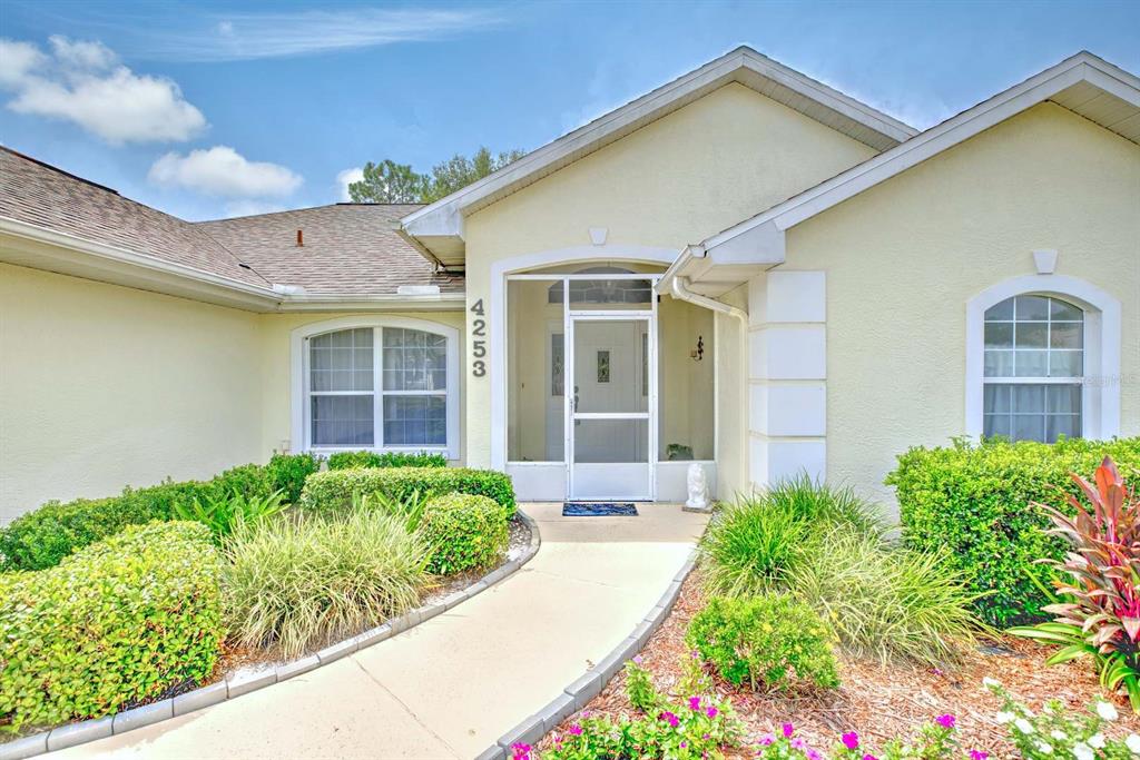 The exterior of a light-colored house features a screened entryway and a paved walkway — 4253 CREMONA DRIVE, SEBRING, FL