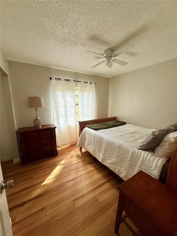A bedroom features a bed, a wooden dresser, a ceiling fan, and hardwood flooring — 9402 N SEMMES STREET, TAMPA, FL