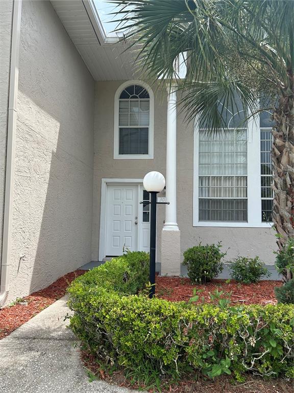 The exterior of a home features a white front door, a tall column, and landscaping — 3076 SHINGLE CREEK COURT, KISSIMMEE, FL