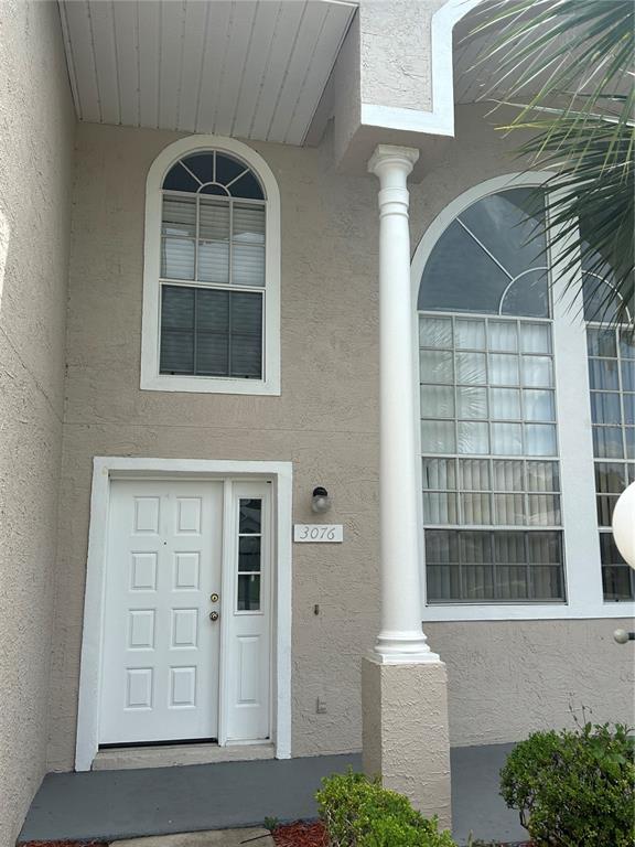 The exterior of a beige house features a white front door, a tall column, and arched windows — 3076 SHINGLE CREEK COURT, KISSIMMEE, FL