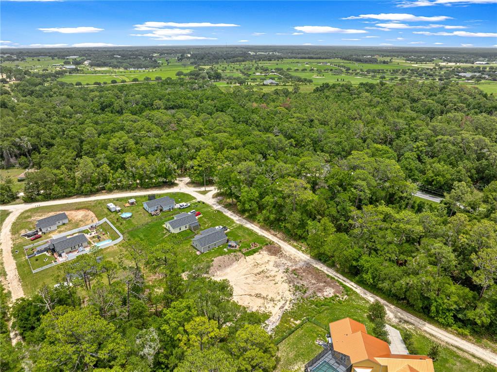 An aerial view shows several houses surrounded by dense forest and open grassy fields — SW 41ST STREET ROAD, OCALA, FL