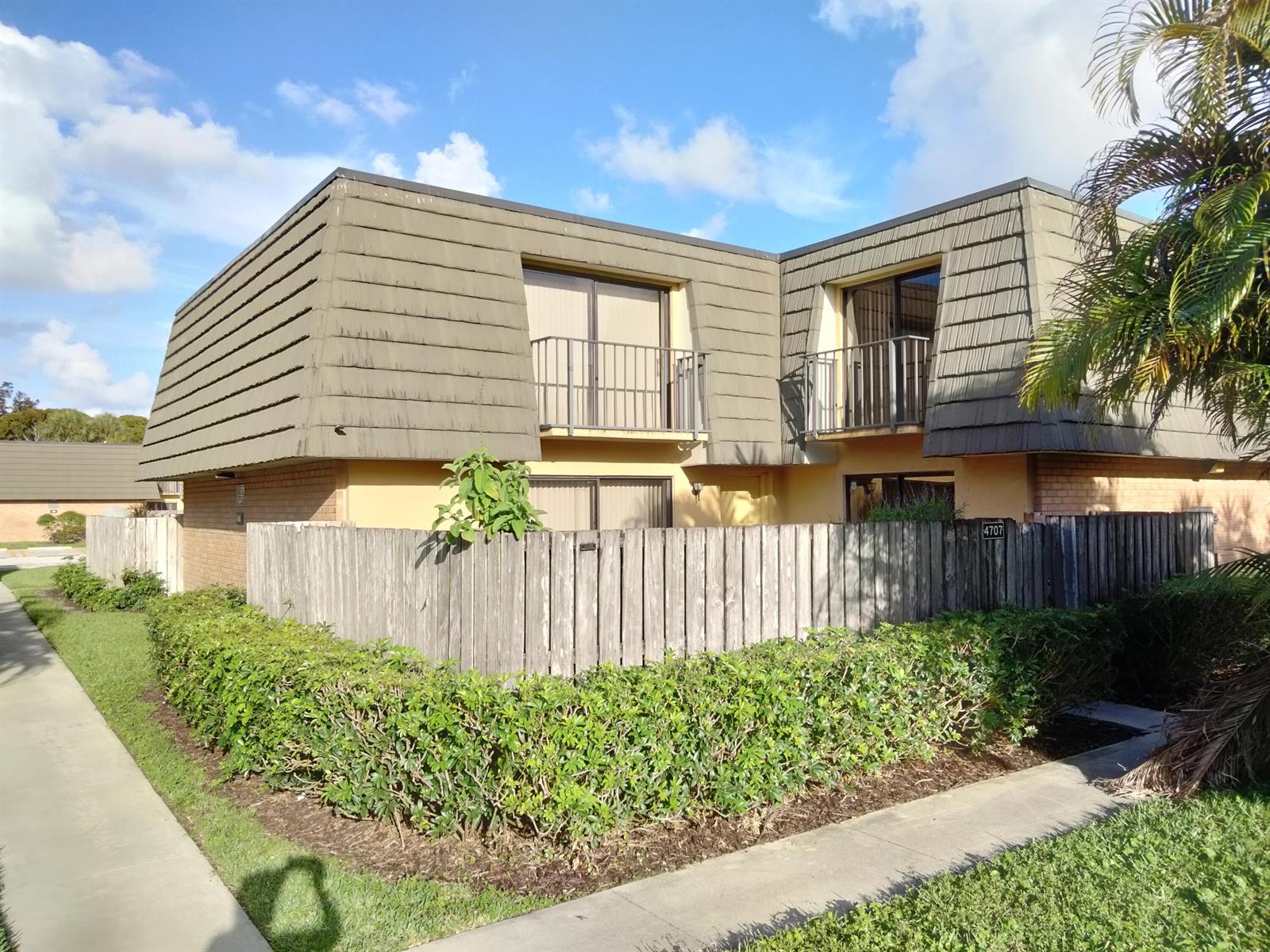 An empty bedroom with light wood flooring, mirrored closet doors, and an attached bathroom — 4707 47th Way, West Palm Beach FL 33407, WEST PALM BEACH, FL