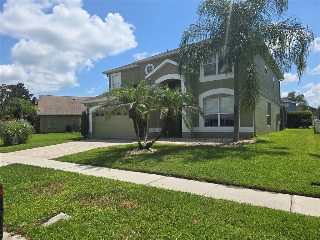 A two-story house with a green stucco exterior, a two-car garage, and palm trees — 1349 WILLOW BRANCH DRIVE, ORLANDO, FL