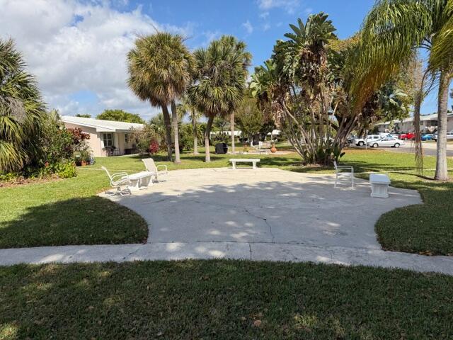 A concrete patio with outdoor seating is surrounded by a grassy lawn and palm trees — 3801 NE 22nd Terrace # 12, Lighthouse Point FL 33064, LIGHTHOUSE POINT, FL