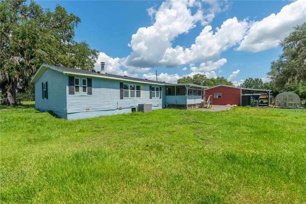 A light blue house with a screened porch sits on a large, grassy rural lot — 88 CULBREATH ROAD, BROOKSVILLE, FL
