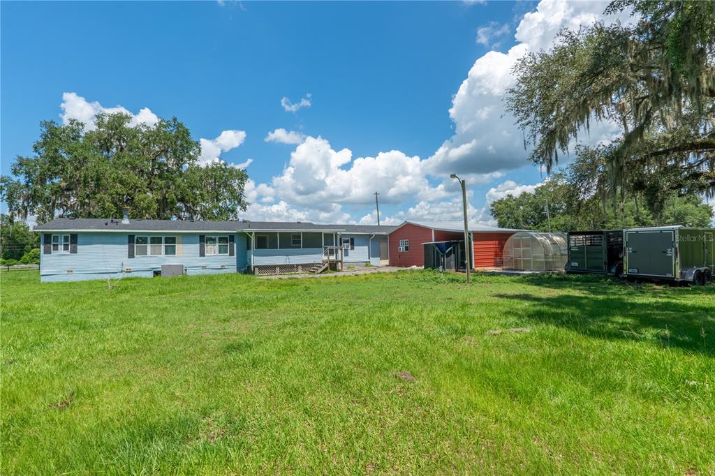 A blue manufactured home with an attached red metal building and a greenhouse in back — 88 CULBREATH ROAD, BROOKSVILLE, FL