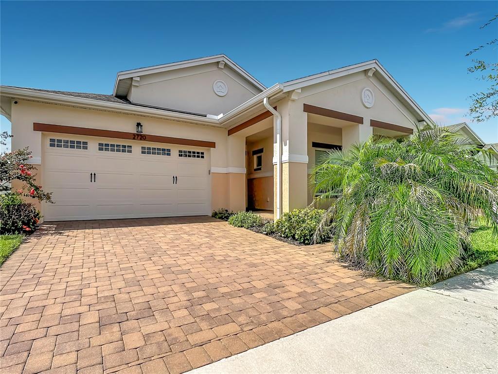 A single-story house with a paved driveway, a two-car garage, and a palm tree — 2720 GREENLANDS STREET, ST CLOUD, FL
