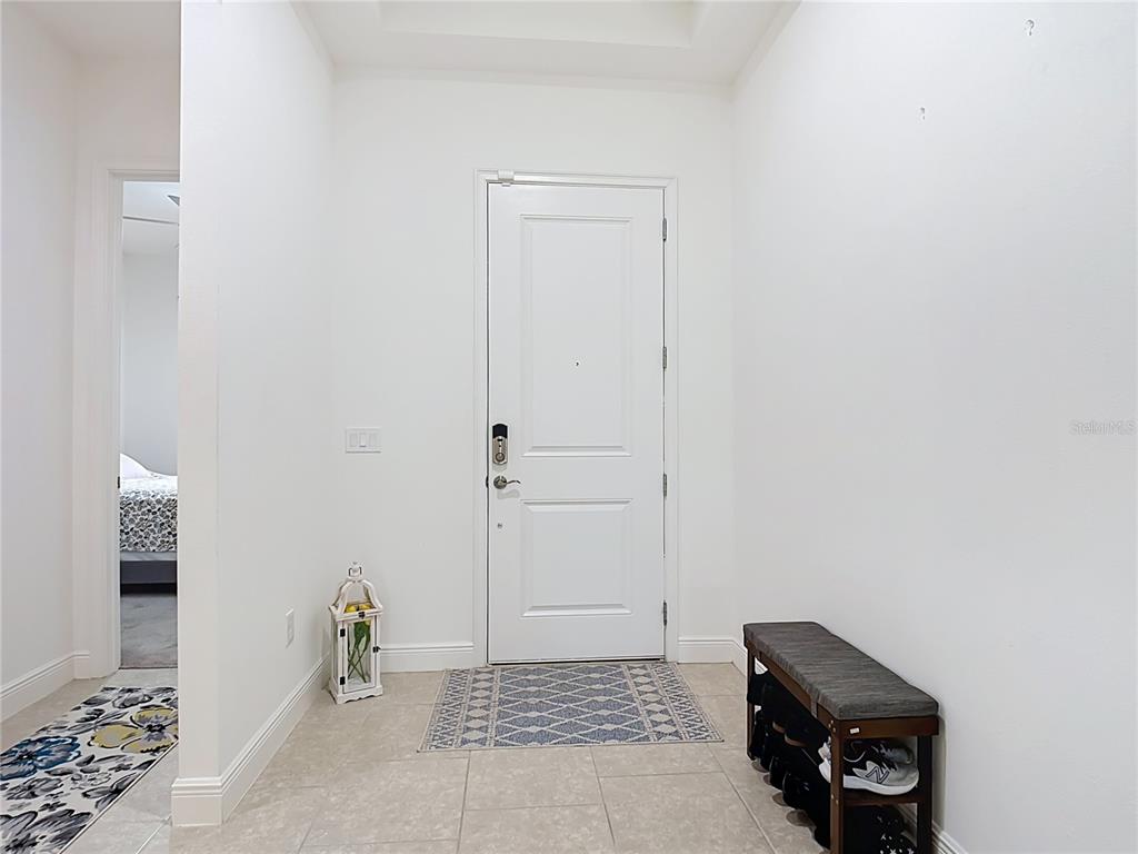 An entryway features a white door, tile flooring, a shoe bench, and a decorative lantern — 2720 GREENLANDS STREET, ST CLOUD, FL