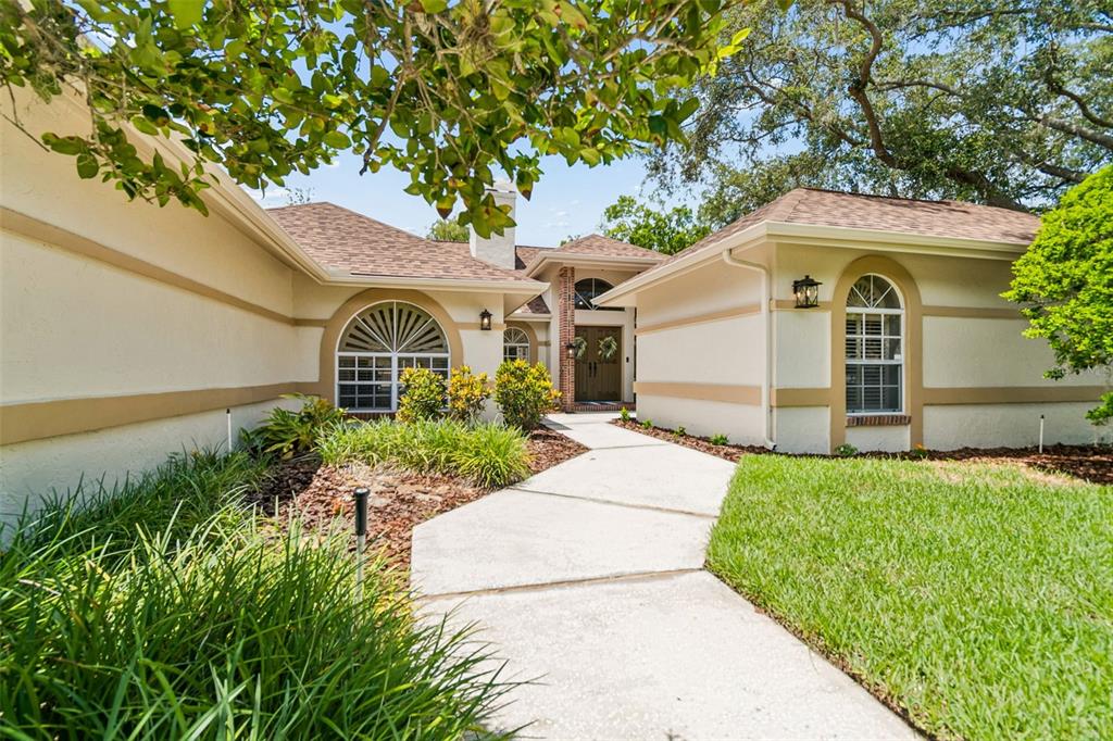 The exterior of a house features a brick-columned entryway with double doors and arched windows — 18106 FAIRMEAD COURT, LUTZ, FL