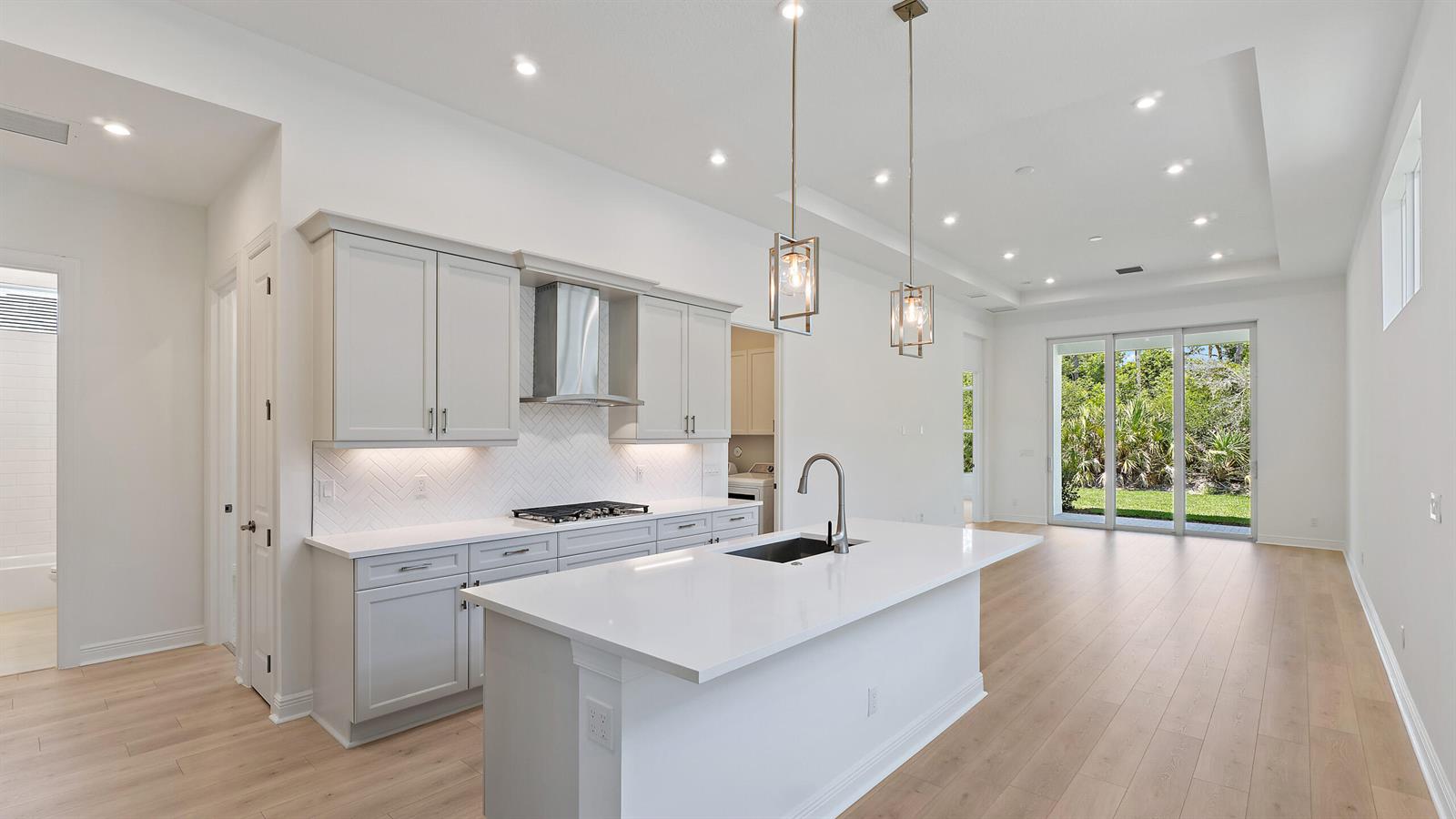 A modern kitchen features light gray cabinets, white countertops, a central island, and wood flooring — 212 SE Via Sangro, FL 34952, FL