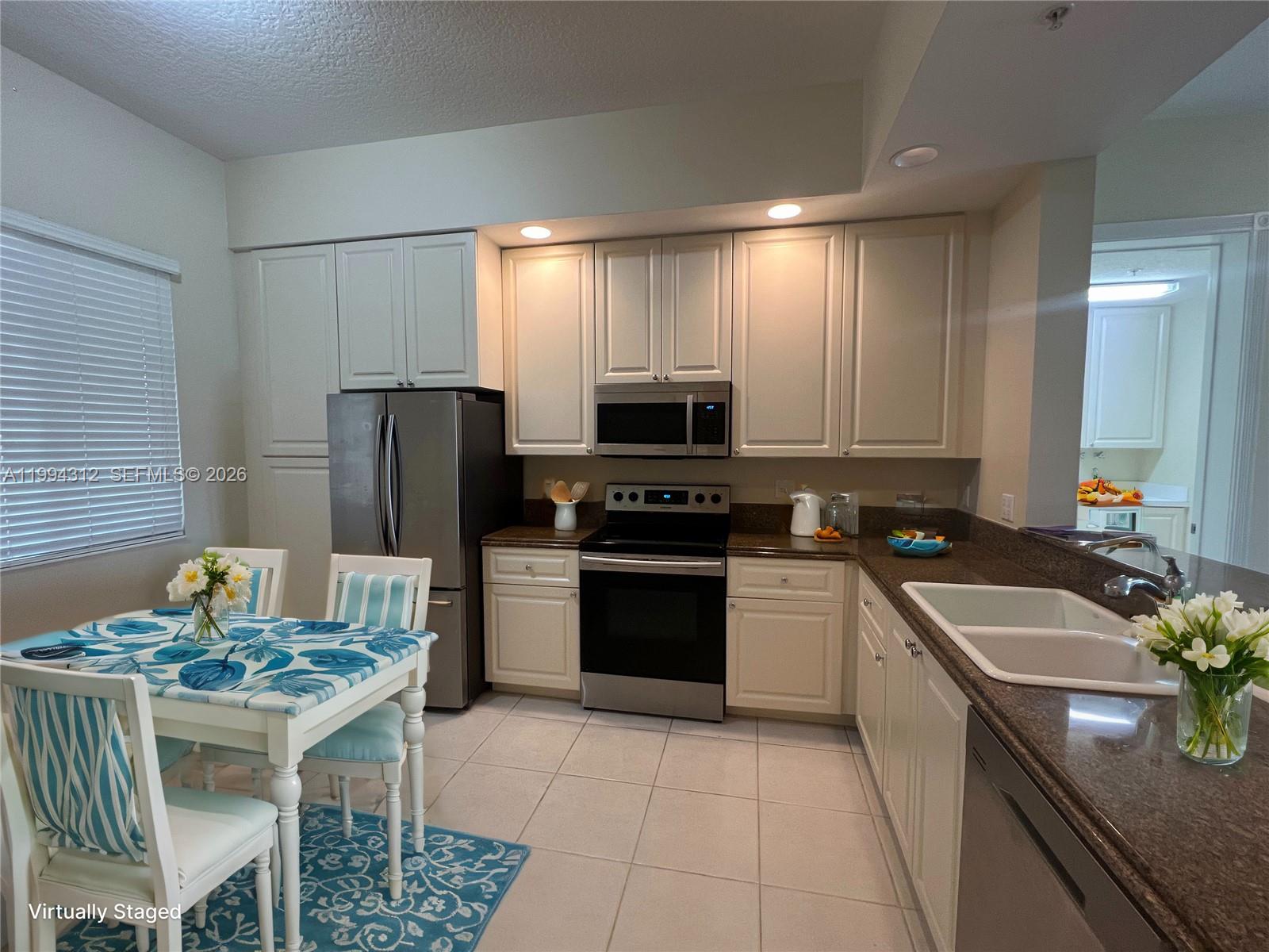 A kitchen features white cabinets, stainless steel appliances, brown countertops, and a dining area — 5 E Harbour Isle # 306, Fort Pierce FL 34949, FORT PIERCE, FL