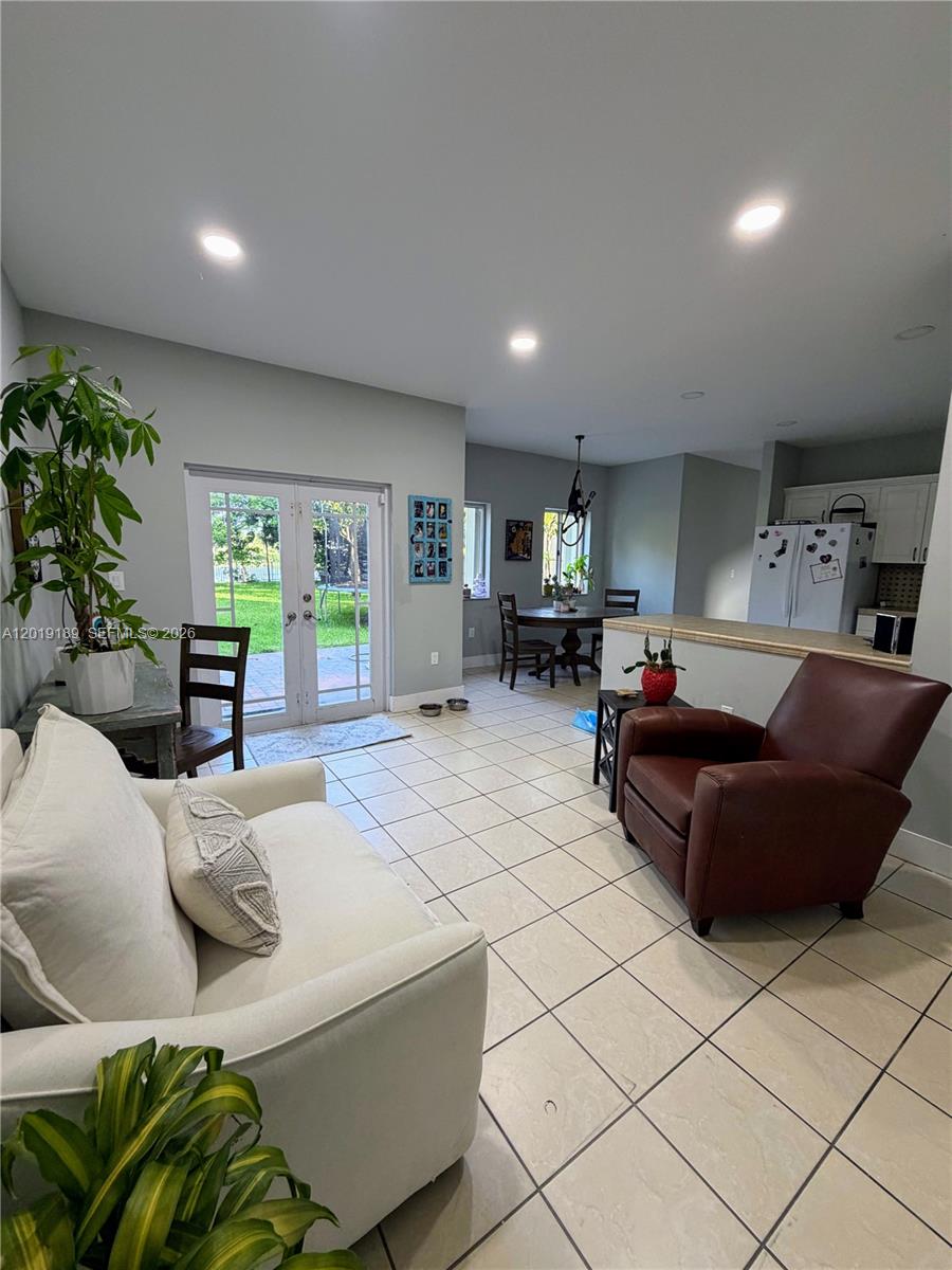 A living room with tile floors, a white sofa, and a brown leather armchair — 4124 NE 30th St, Homestead FL 33033, HOMESTEAD, FL