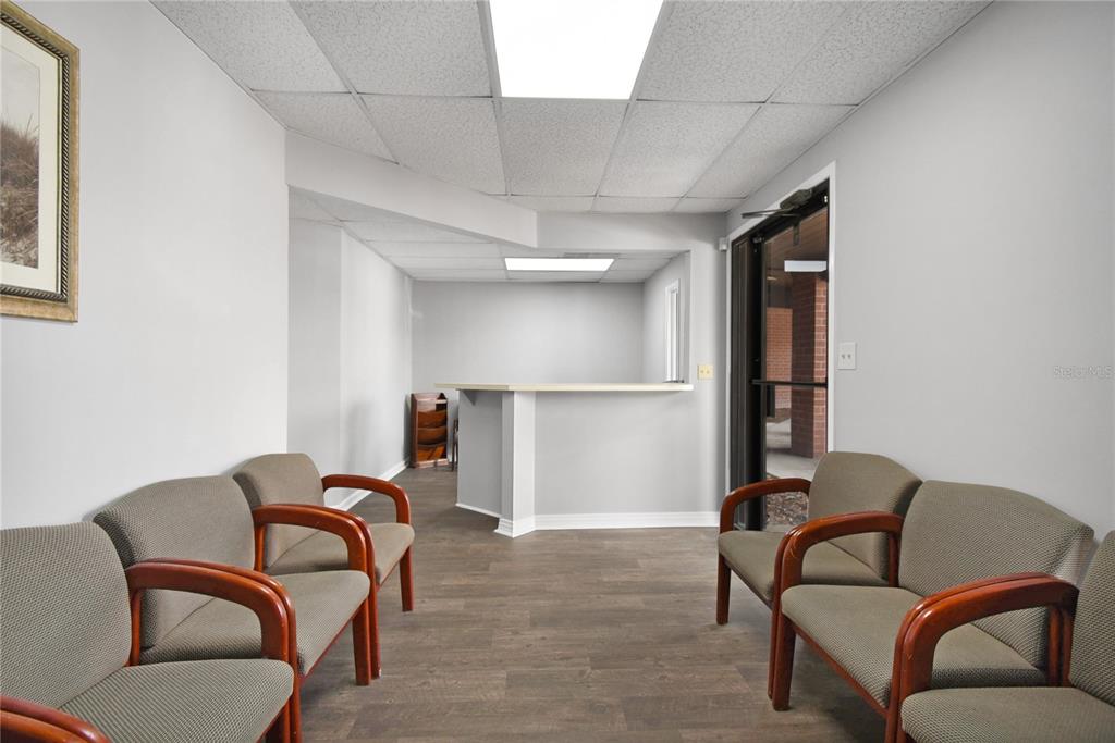 A waiting room features gray walls, wood-look flooring, a reception counter, and four upholstered chairs — 1840 DUNN AVENUE UNIT 5, JACKSONVILLE, FL