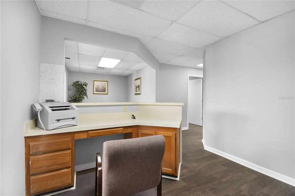 A reception desk with a printer sits in a room with gray walls and flooring — 1840 DUNN AVENUE UNIT 5, JACKSONVILLE, FL