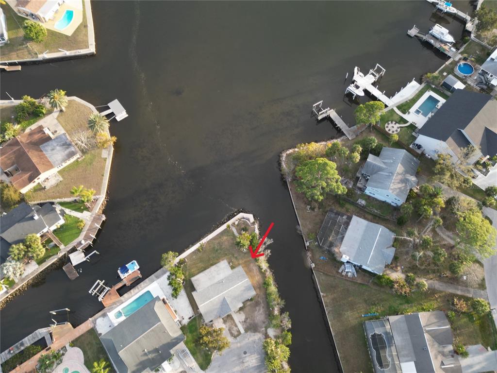 An aerial view shows a waterfront house with a red arrow pointing toward the property — 8402 DAMEN LANE, PORT RICHEY, FL