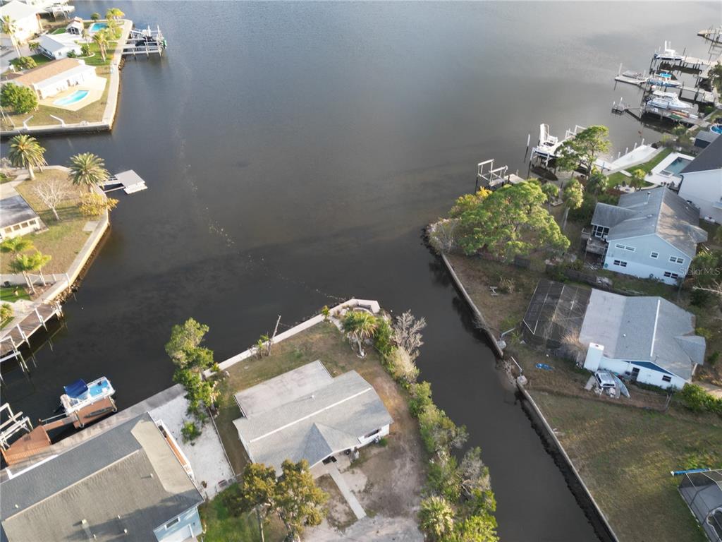 An aerial view shows waterfront homes with private docks along a canal and bay — 8402 DAMEN LANE, PORT RICHEY, FL
