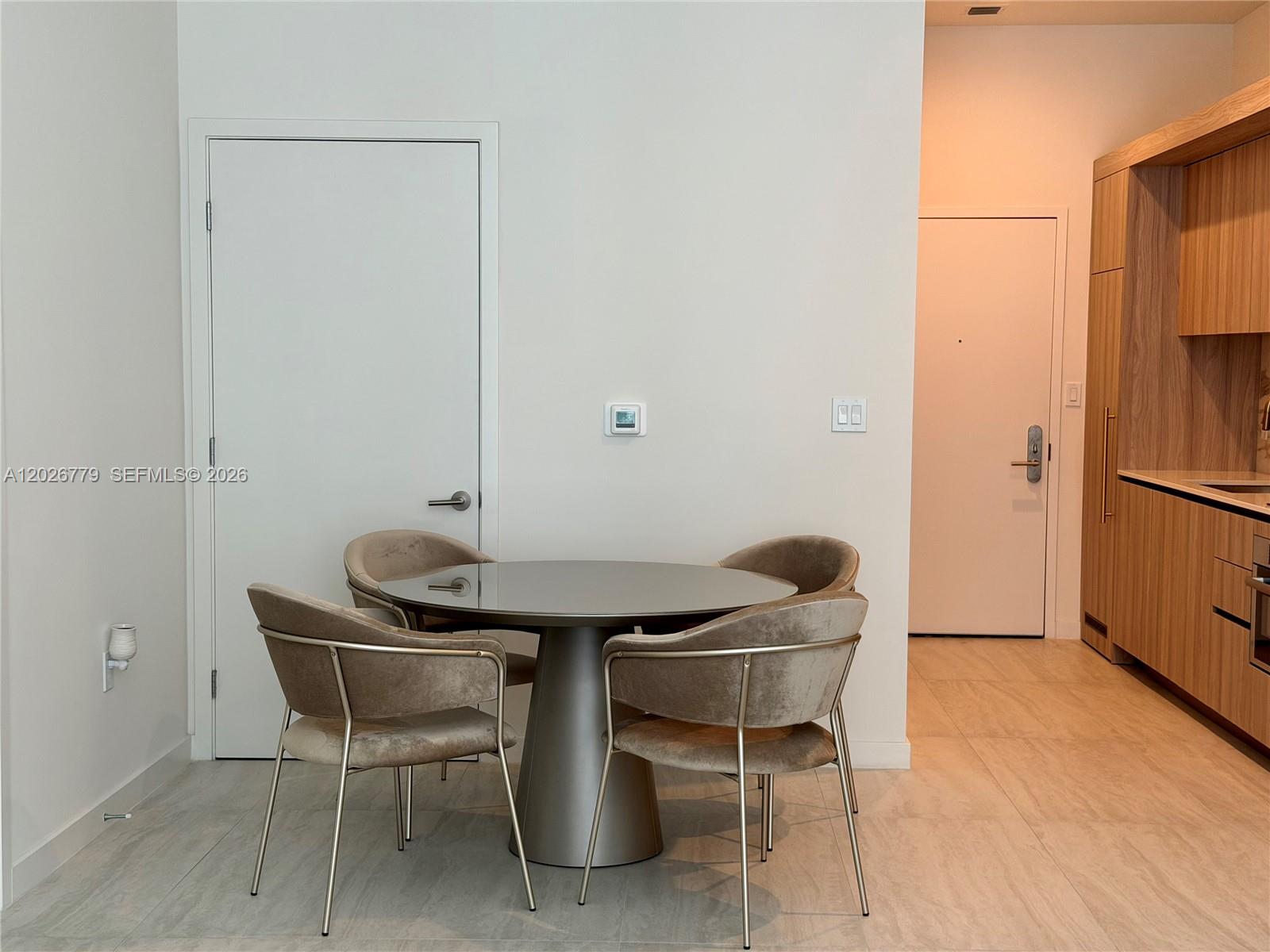 A dining area features a round table with four velvet chairs near a kitchen — 77 SE 5th St # 407, Miami FL 33131, MIAMI, FL