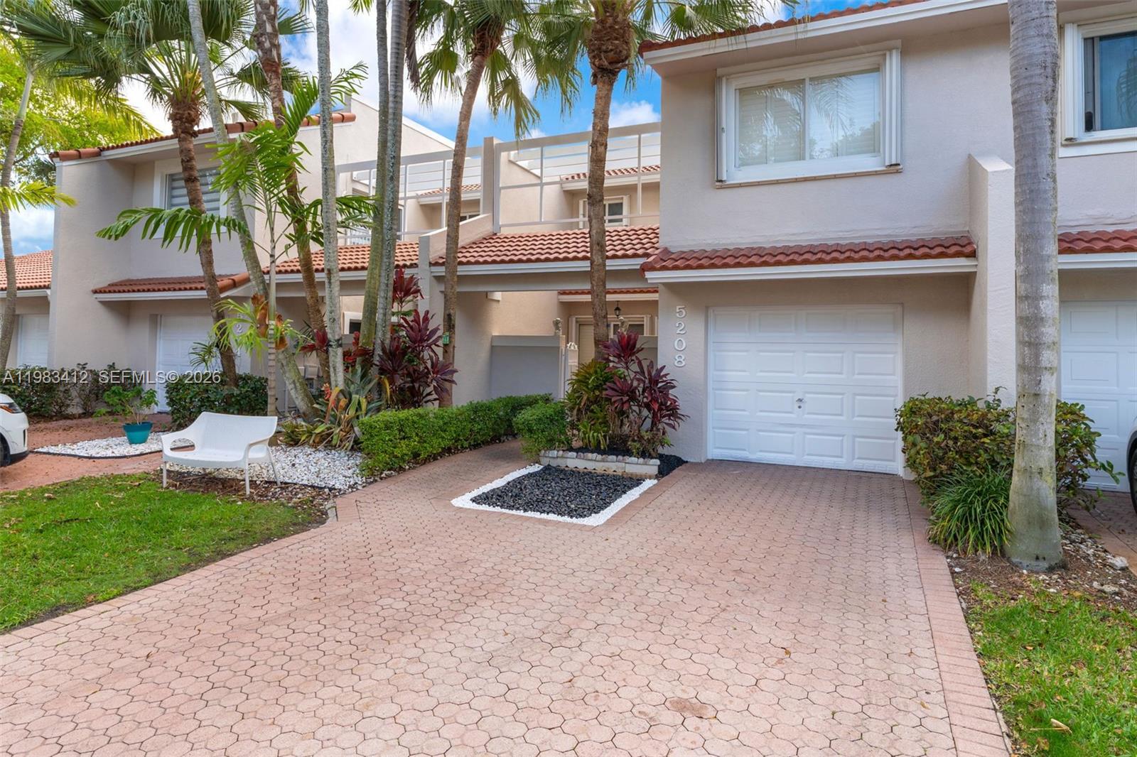 A two-story townhouse with a paved driveway, white garage door, and palm trees — 5208 NW 103rd Ave, Doral FL 33178, DORAL, FL