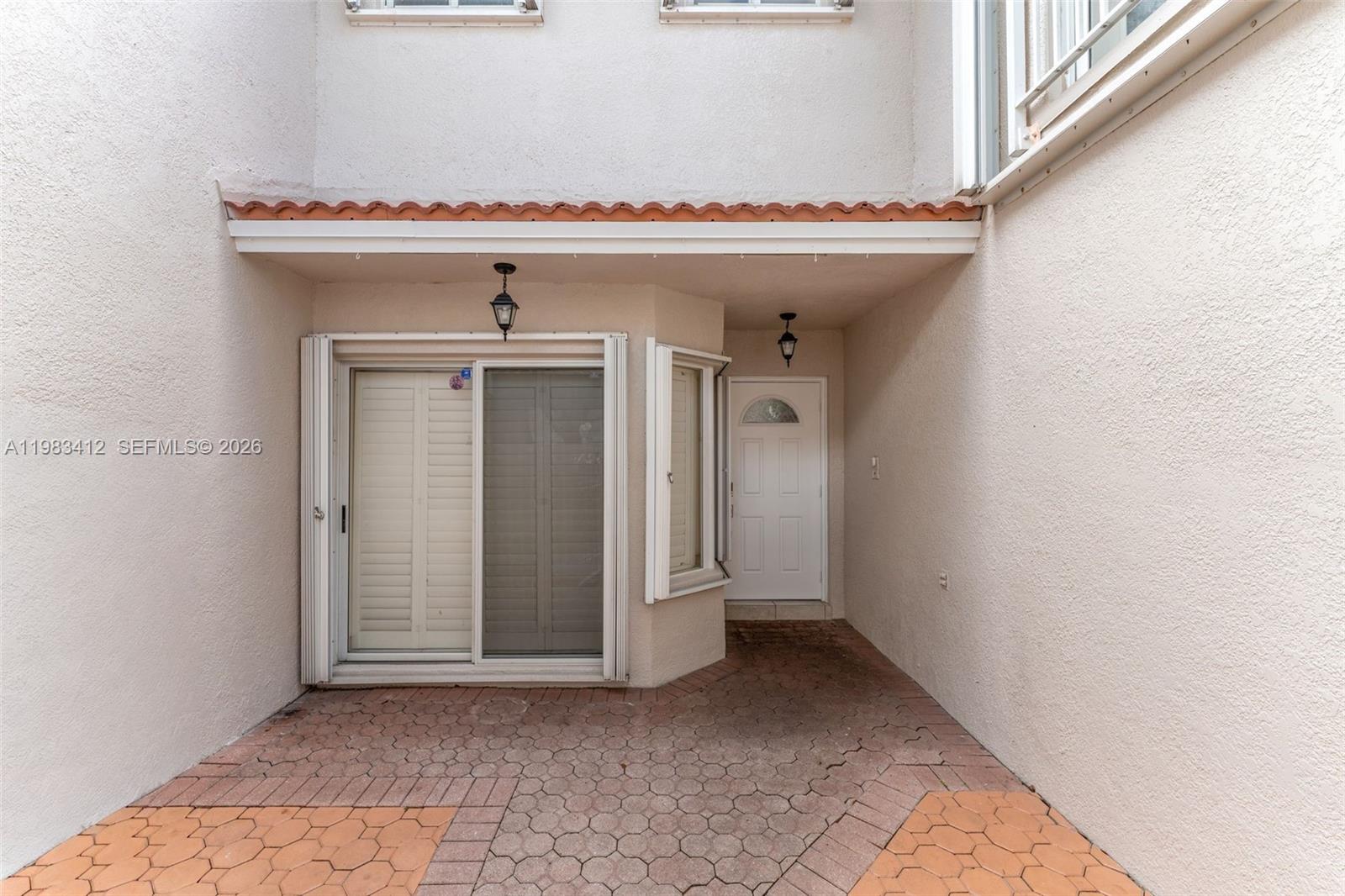 A paved patio area features a sliding glass door and a white front door — 5208 NW 103rd Ave, Doral FL 33178, DORAL, FL