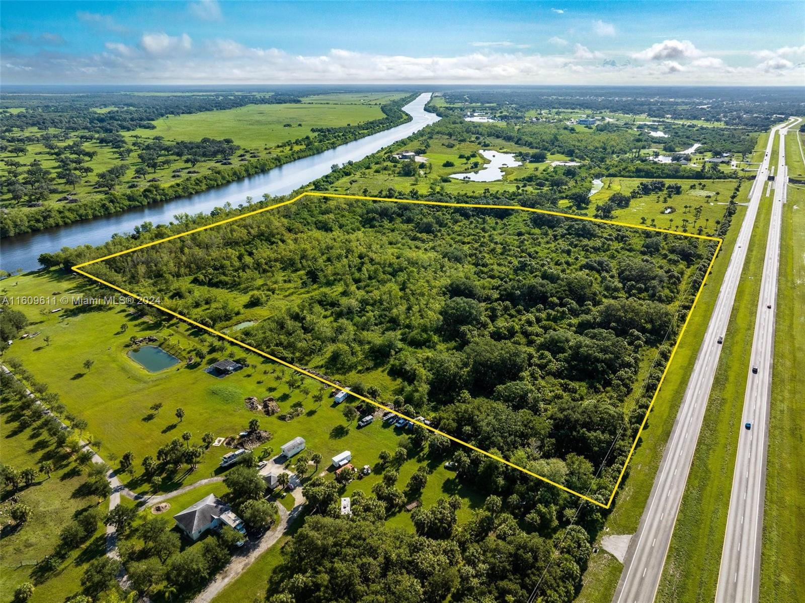 An aerial view shows a large, rectangular wooded lot bordered by a river and highway — 1984 E State Road 80, La Belle FL 33935, LA BELLE, FL