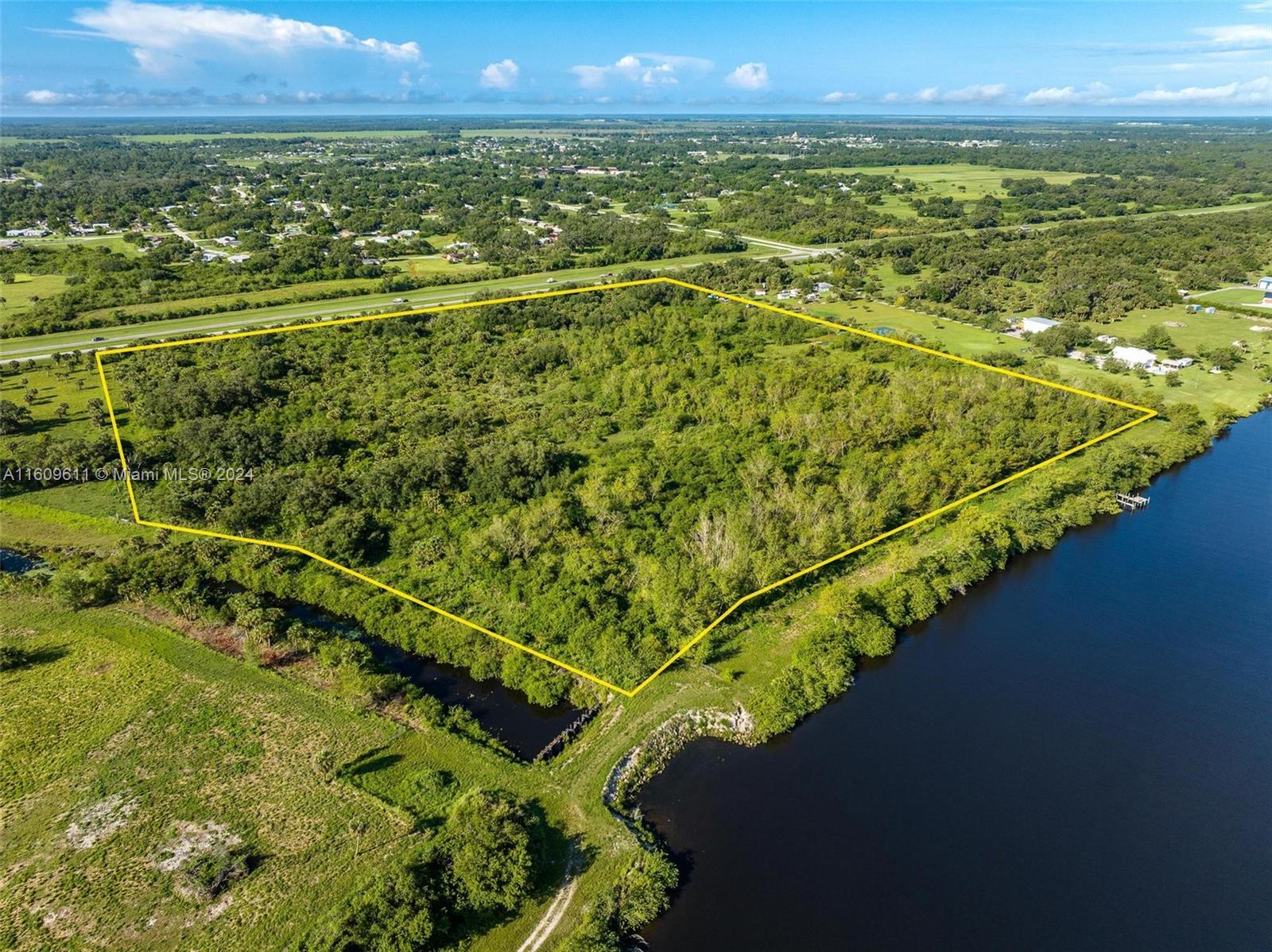 An aerial view shows a large, rectangular, tree-covered plot of land bordering a river — 1984 E State Road 80, La Belle FL 33935, LA BELLE, FL