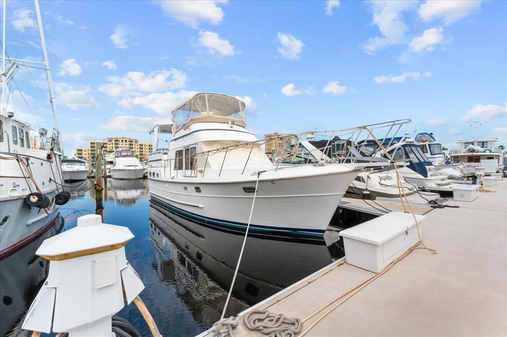 A white motor yacht is docked at a marina under a blue sky with clouds — 102 RIVIERA DUNES WAY UNIT S-39, PALMETTO, FL