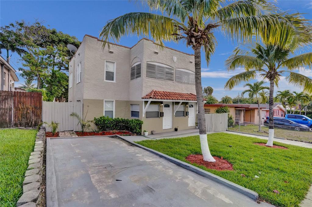 A two-story stucco duplex with a concrete driveway, palm trees, and a red tile awning — 924 MCINTOSH STREET, WEST PALM BEACH, FL