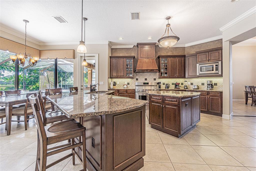 A kitchen with dark wood cabinets, granite countertops, a center island, and tile flooring — 20411 LACE CASCADE ROAD, LAND O LAKES, FL