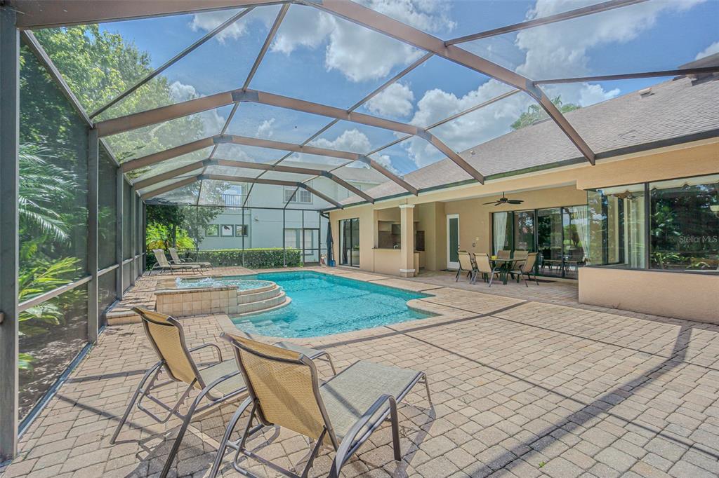 A screened-in patio features a swimming pool, a hot tub, and outdoor dining furniture — 20411 LACE CASCADE ROAD, LAND O LAKES, FL