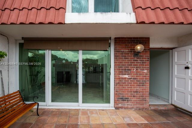 A patio with a wooden bench, sliding glass doors, and a brick wall exterior — 13949 SW 84th St # 801, Miami FL 33183, MIAMI, FL