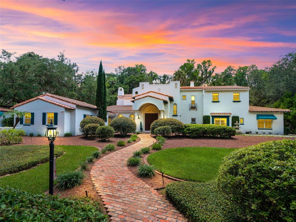 A brick walkway leads to the arched entryway of a two-story Mediterranean-style home at sunset — 4200 SW 7TH AVE ROAD, OCALA, FL