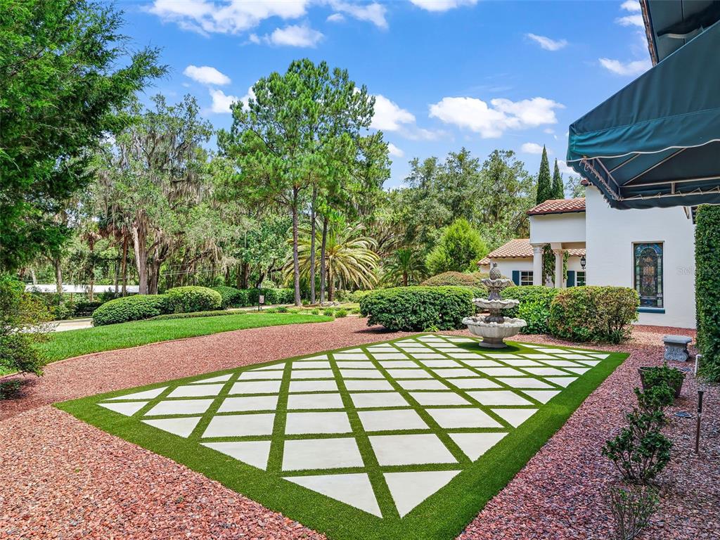 A stone patio with a diamond-patterned grid of pavers and grass sits near a fountain — 4200 SW 7TH AVE ROAD, OCALA, FL