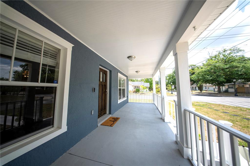 A covered front porch with blue exterior walls, a wooden door, and white railings — 603 W BELMAR STREET, LAKELAND, FL