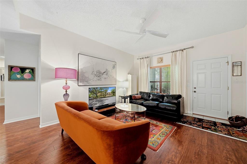A living room features wood flooring, an orange sofa, a black leather sofa, and a rug — 328 LOS PRADOS DRIVE UNIT 328, SAFETY HARBOR, FL