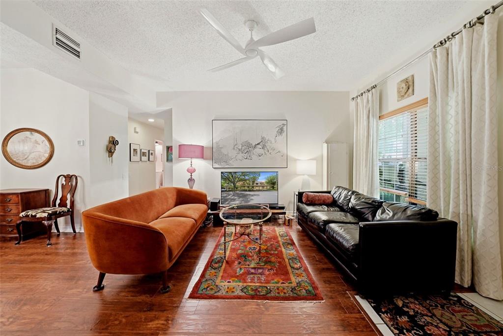 A living room features a burnt orange sofa, a black leather sofa, and a patterned rug — 328 LOS PRADOS DRIVE UNIT 328, SAFETY HARBOR, FL