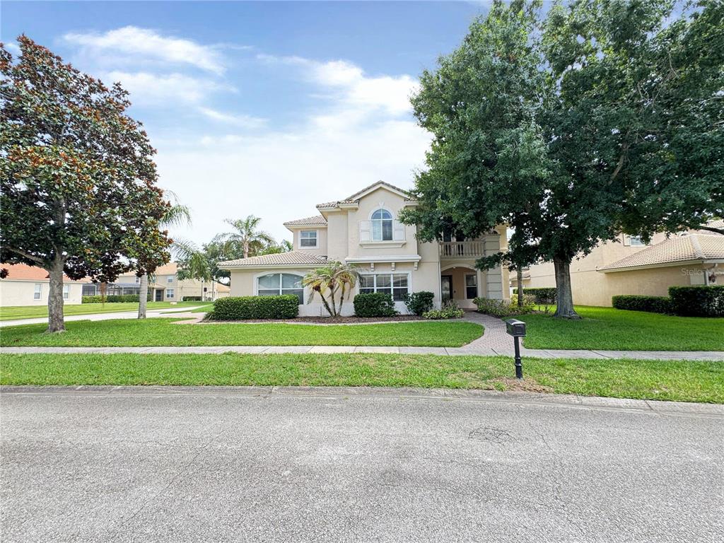 A two-story suburban house with a beige stucco exterior, tile roof, and mature trees — 173 CALLIOPE STREET, OCOEE, FL