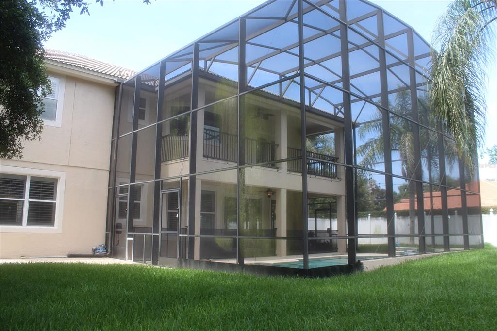 A two-story house features a large screened-in pool enclosure and a grassy backyard — 173 CALLIOPE STREET, OCOEE, FL