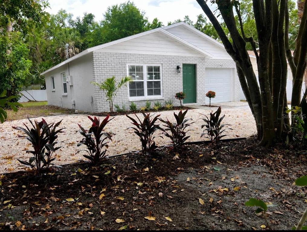 A single-story house with a white brick exterior, green front door, and a gravel driveway — 2542 22ND STREET, SARASOTA, FL