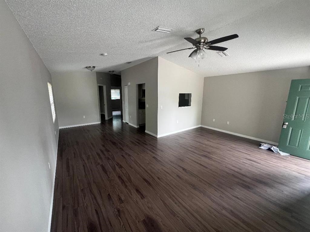 A spacious living room features dark wood-look flooring, light gray walls, and a ceiling fan — 2542 22ND STREET, SARASOTA, FL