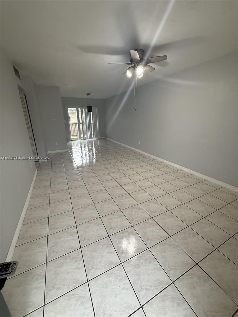 A long, empty room features light gray walls, white tile flooring, and a ceiling fan — 7505 SW 82nd St # 314, Miami FL 33143, MIAMI, FL